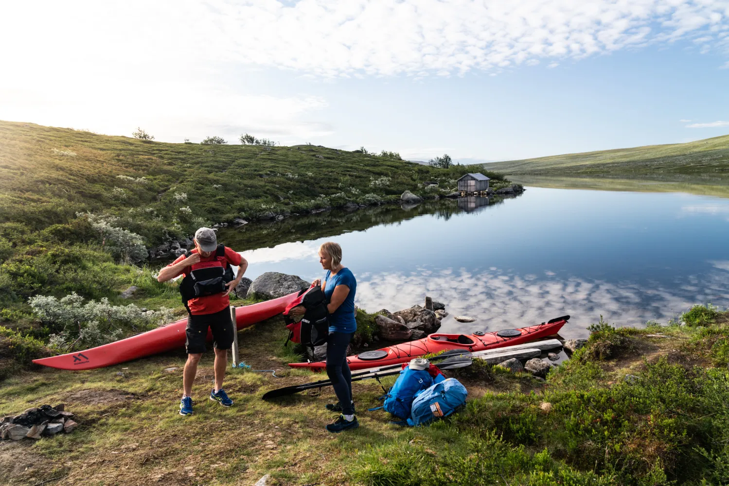 Två personer som förbereder sig på att paddla kayak i en sjö på fjället