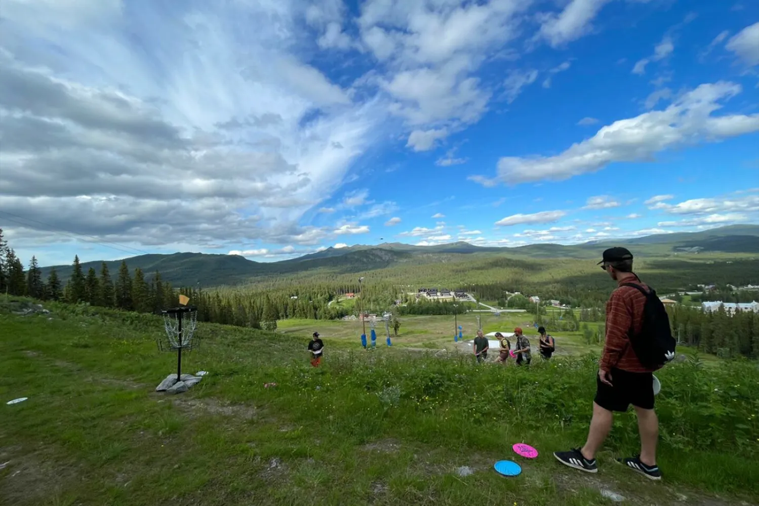 En grupp människor spelar discgolf på en gräsbevuxen kulle