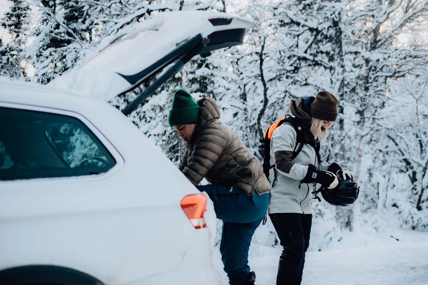 Bil i snölandskap med personer som gör sig redo för en dag i skidbacken