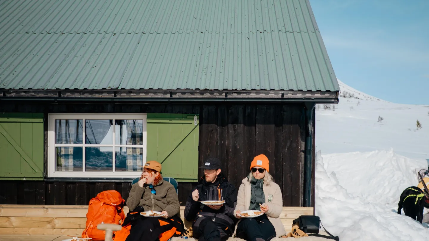 Personer som njuter av en fika en solig dag i snölandskap