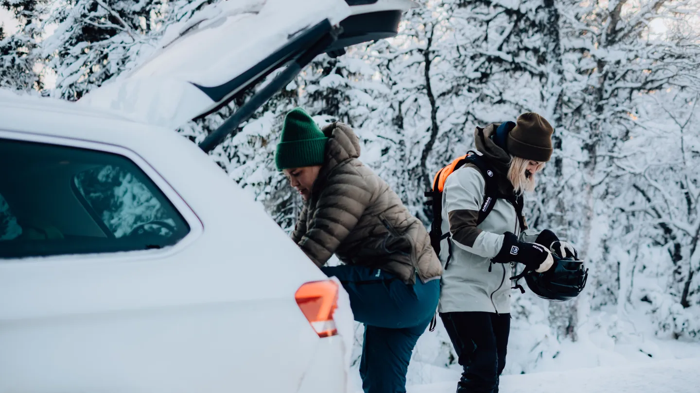 Bil i snölandskap med personer som gör sig redo för en dag i skidbacken